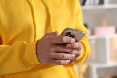 Ergen çocuk evde akıllı telefon kullanıyor, yakın plan.