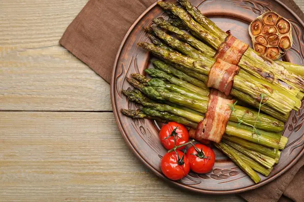 Ahşap masada domuz pastırması ve baharatla servis edilen lezzetli pişmiş kuşkonmaz. Metin için boşluk