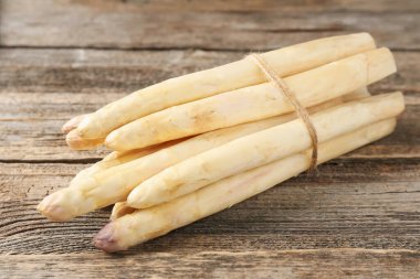 Ahşap masada çiğ beyaz kuşkonmaz mızrakları, yakın plan.