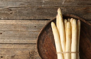 Ahşap masanın üstünde çiğ beyaz kuşkonmaz mızrakları. Metin için boşluk