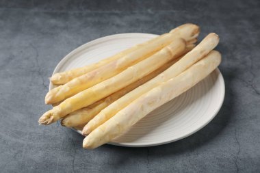 Gri desenli masada çiğ beyaz kuşkonmaz mızrakları, yakın plan.