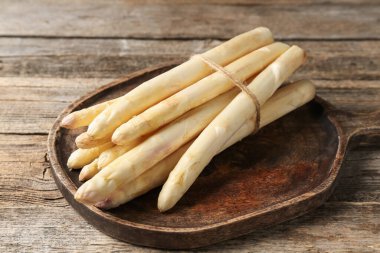 Ahşap masada çiğ beyaz kuşkonmaz mızrakları, yakın plan.