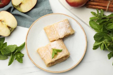 Lezzetli elmalı turta parçaları pudra şekeri, nane, meyve ve tarçın beyaz mermer masa, düz yatıyordu