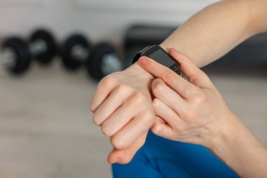 Kadın spor salonunda spor yaparken takip cihazını kontrol ediyor, yakın plan. Metin için boşluk