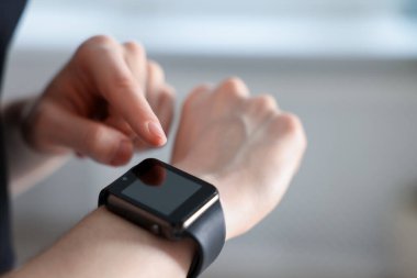 Kadın spor salonunda spor yaparken takip cihazını kontrol ediyor, yakın plan.