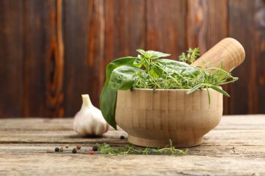 Kabuklu havan, ahşap masada farklı aromatik otlar ve baharatlar, yakın plan. Metin için boşluk