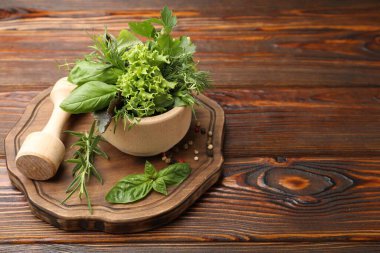 Kabuklu havan, ahşap masada farklı aromatik otlar ve baharatlar, metin için yer