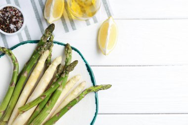 Beyaz ahşap masa üzerinde farklı çiğ kuşkonmaz mızrakları ve baharatlar. Metin için boşluk