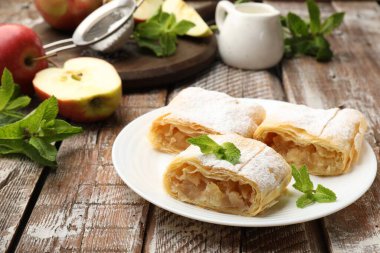 Lezzetli elmalı turta parçaları pudra şekeri, nane ve ahşap masada meyveler, yakın plan.