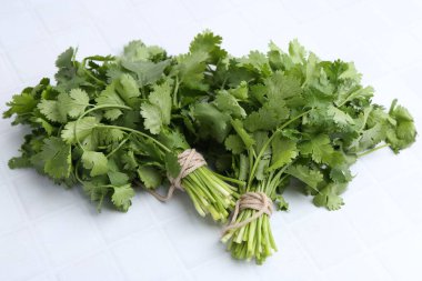 Beyaz fayanslı masada taze aromatik kişniş, yakın plan.