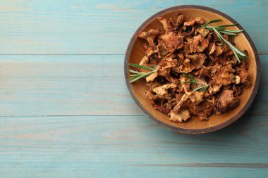 Mavi ahşap masa üzerinde biberiyeli kurutulmuş chanterelle mantarı. Metin için boşluk