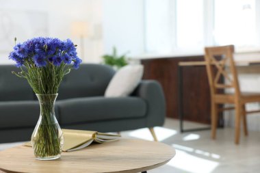 Vazodaki güzel mavi çiçek ve evdeki ahşap masada kitap. Metin için boşluk