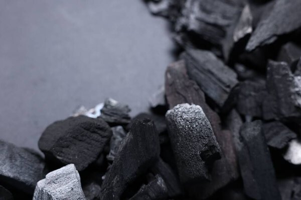 Куски черных углей на сером фоне, крупным планом. Пространство для текста