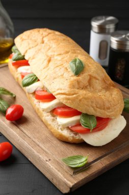 Mozarella peynirli, domatesli, fesleğenli, siyah ahşap masa, yakın plan.