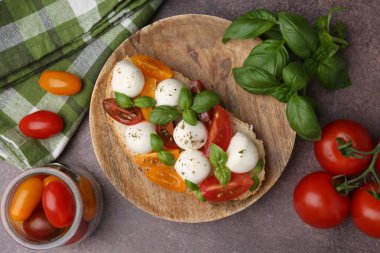 Peynirli, domatesli, kahverengi sehpada fesleğenli lezzetli bir sandviç.