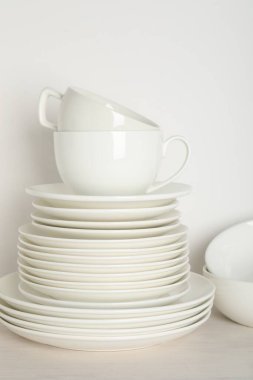 Beyaz duvarın yanındaki açık ahşap masada farklı temiz bulaşık takımı.