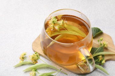 Fincanda taze ıhlamur çayı ve açık gri masada çiçekler, yakın plan. Metin için boşluk