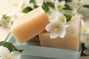Bej arka planda sabun ve yasemin çiçekleri, yakın plan.
