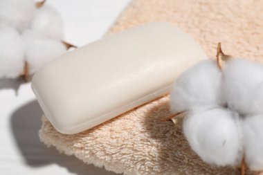 Sabun çubuğu, pamuk çiçekleri ve havlu beyaz masada, yakın plan.