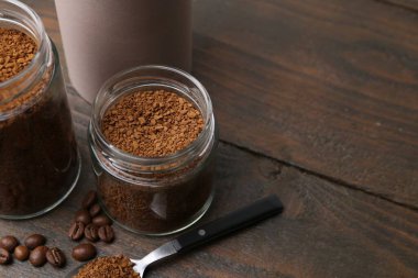 Kavanozlarda hazır kahve ve ahşap masada fasulye, yakın plan. Metin için boşluk