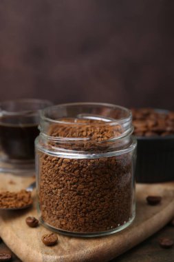 Cam kavanozdaki anlık kahve, masada sıcak içecek ve fasulye, yakın plan.