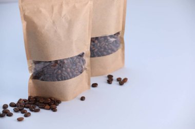 Açık gri arka planda kahve çekirdekli fermuar stand-up torbaları, yakın plan. Tasarım için model