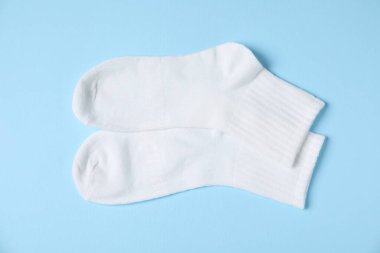 Açık mavi arka planda bir çift rahat beyaz çorap, üst manzara