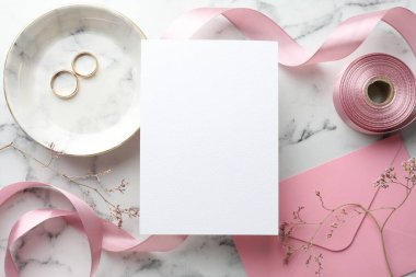 Düğün davetiyesi, altın yüzükler, kurdele, zarf ve dallar beyaz mermer masa, düz yatıyordu.