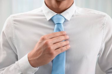 Evde şık kravat bağlayan adam, yakın plan.