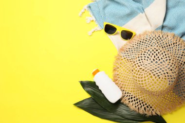 Plaj havlusuyla düz kompozisyon ve sarı arka planda diğer yaz aksesuarları. Metin için boşluk