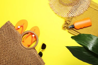Plaj havlusuyla düz kompozisyon ve sarı arka planda diğer yaz aksesuarları.