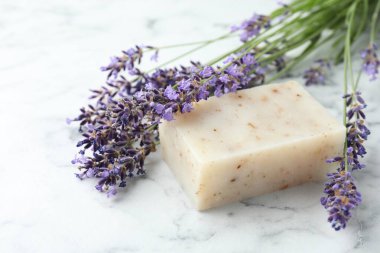 Sabun çubuğu ve lavanta çiçekleri beyaz mermer masada, yakın plan.