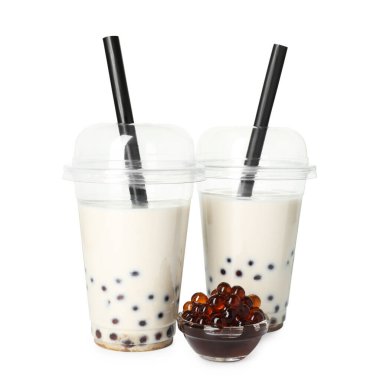 Plastik bardakta lezzetli sütlü çay ve beyaz bardakta izole edilmiş muhallebi incileri.