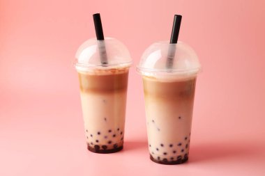 Pembe arka planda plastik bardakta lezzetli sütlü çay.