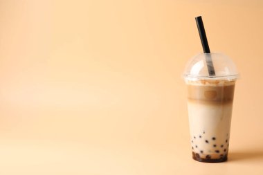 Bej arka planda plastik fincanda lezzetli sütlü çay, metin için yer