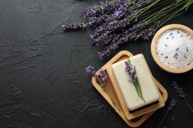 Aromatik sabun çubuğu, deniz tuzu ve lavanta çiçekleri koyu dokulu masa, düz yatak. Metin için boşluk