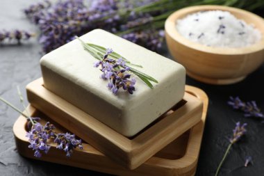 Aromatik sabun barı ve lavanta çiçekleri koyu dokulu masa üzerinde, yakın plan.