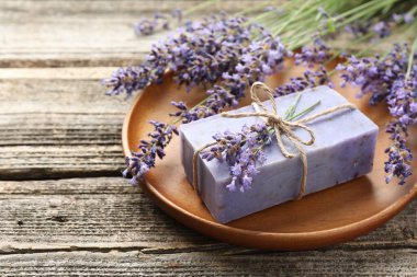 Aromatik sabun barı ve lavanta çiçekleri ahşap masada, yakın plan.