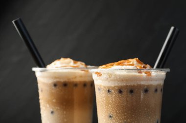 Siyah arka planda plastik fincanlarda lezzetli sütlü çay, yakın plan.