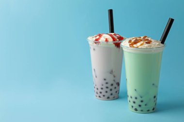 Açık mavi arka planda plastik bardakta lezzetli sütlü çay. Metin için boşluk