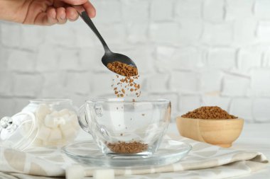 Işık masasında hazır kahveyi fincana koyan kadın, yakın plan.