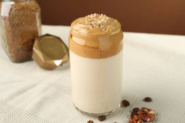 Bardakta lezzetli dalgona kahvesi, fasulye, ceviz ve granüller masada, yakın plan.