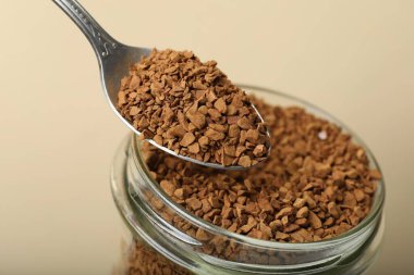 Bej arka planda kaşıkla hazır kahve içmek, yakın plan.