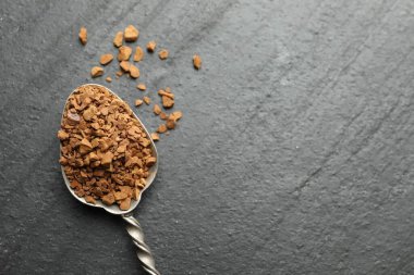 Siyah sehpanın üstünde hazır kahve olan kaşık, üst manzara. Metin için boşluk