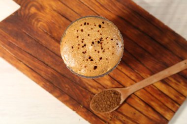 Bardakta enfes dalgona kahvesi ve ışık masasında granüller.