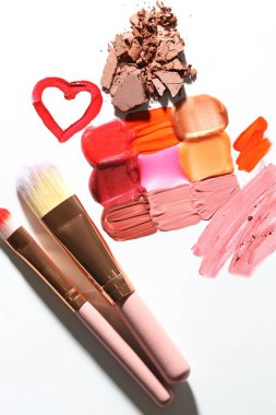 Beyaz arka planda farklı kozmetik ürünler ve makyaj fırçaları, düz yatış