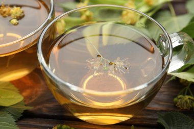 Fincanlarda taze ıhlamur çayı ve ahşap masada çiçekler, yakın plan.