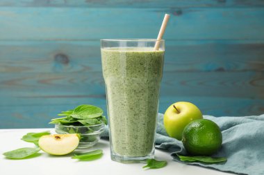 Lezzetli ıspanaklı smoothie ve beyaz mermer masada malzemeler, yakın plan.