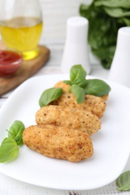 Lezzetli kızarmış kroket ve fesleğen beyaz ahşap masada, yakın plan.