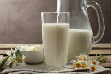 Taze süt, mozarella topları ve ahşap masada çiçekler, yakın plan. Süt ürünleri